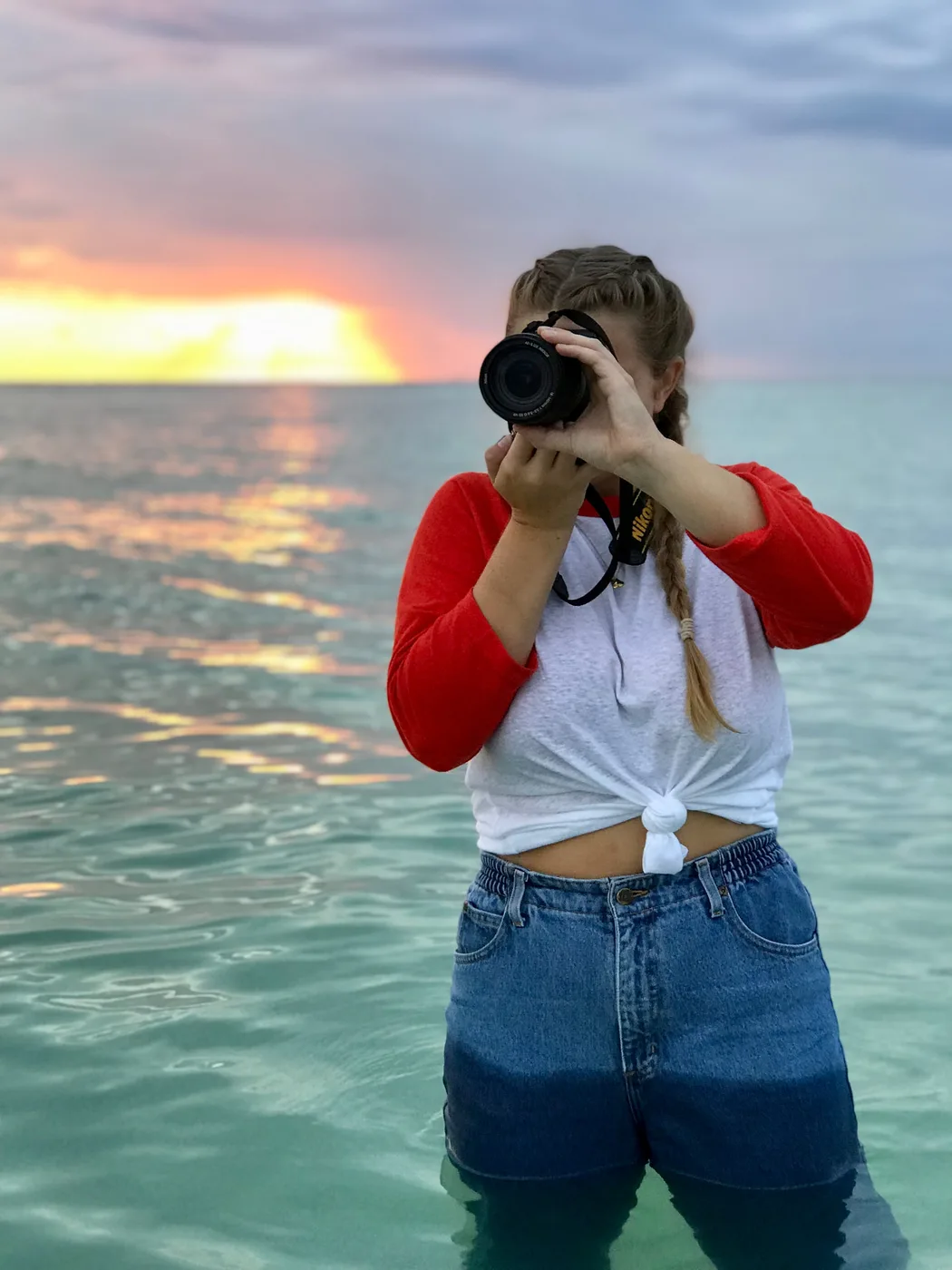 Blue Sitten shooting standing in the ocean at sunset