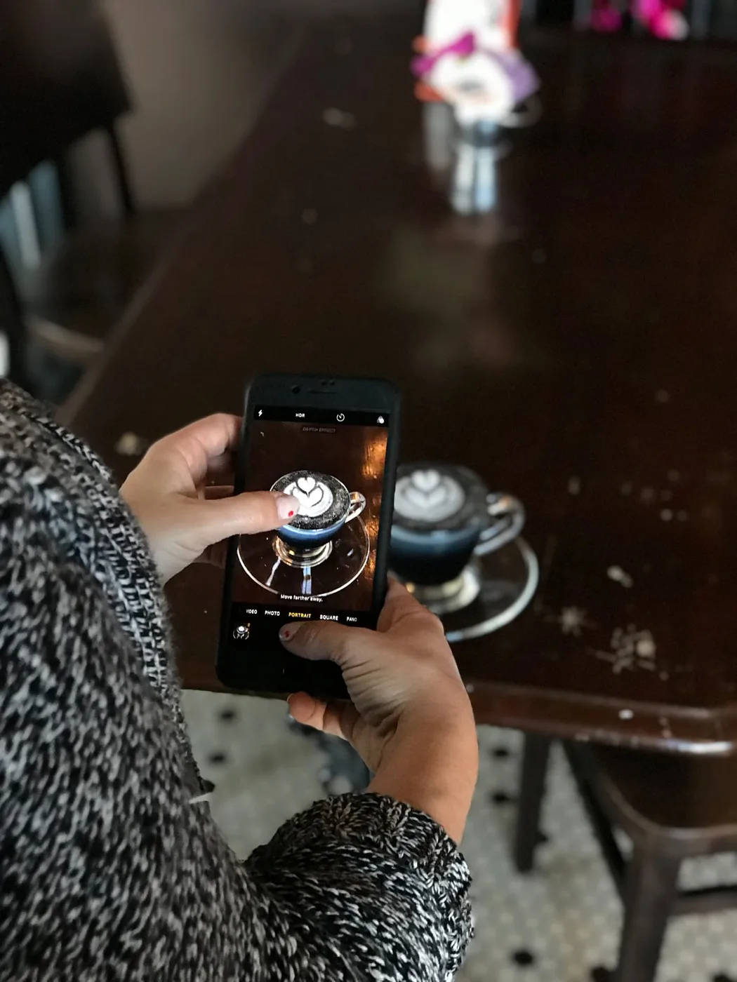 Shooting a latte on a phone in portrait mode at a cafe table