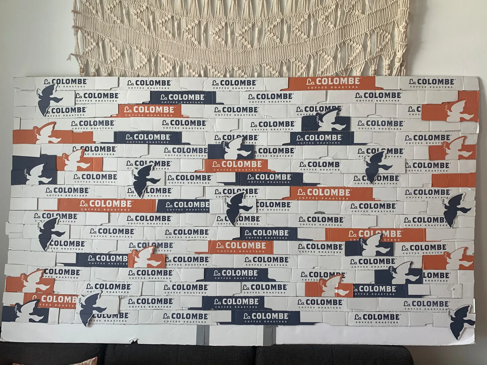 Photo backdrop hand built by Blue Sitten from recycled La Colombe product boxes, tiled like brickwork with cut-out dove marks
